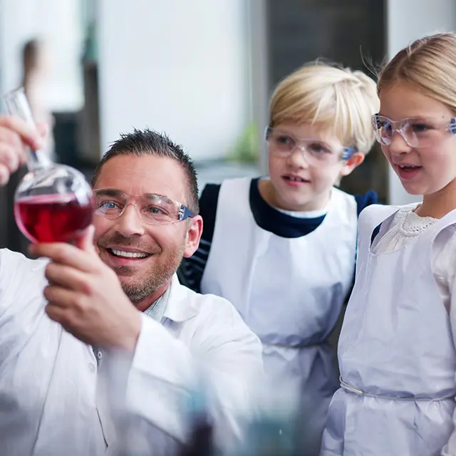 To barn og en voksen som holder på med et eksperiment