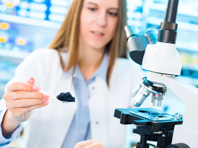 Kvinnelig laborant ser på rogn i forstørrelsesglass